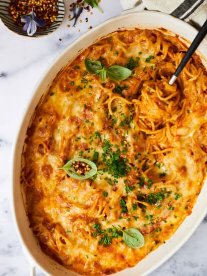 An oval baking dish full of oven baked spaghetti.