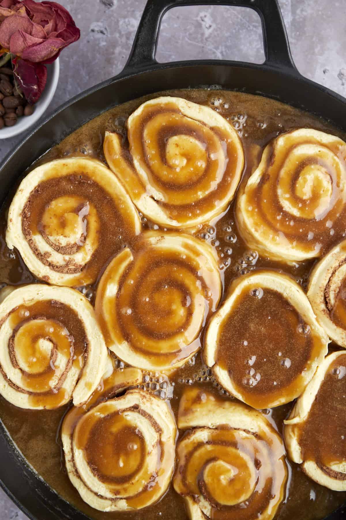 raw cinnamon rolls in a skillet topped with caramel sauce