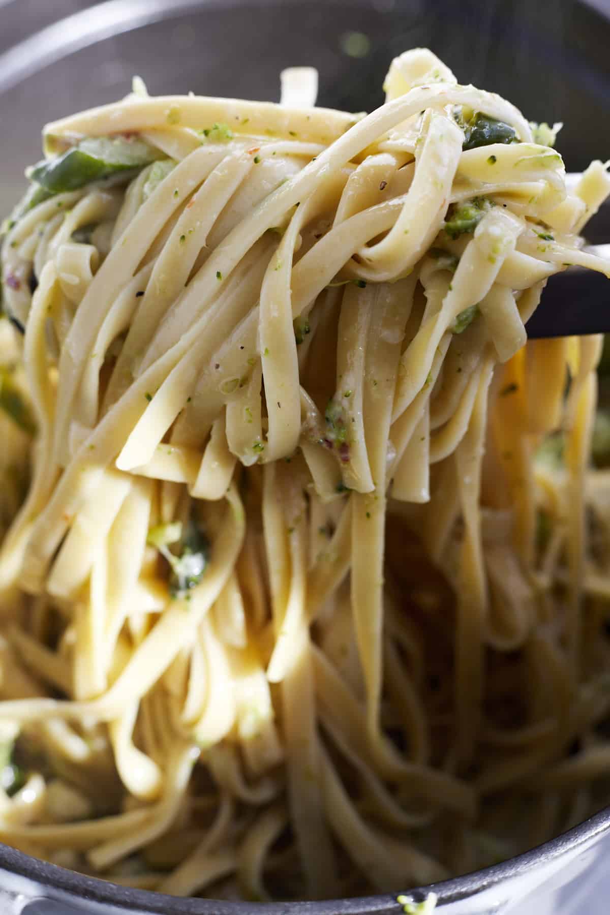 a serving of pasta with veggies being lifted with tongs