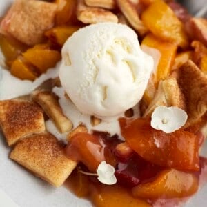 a serving of peach strawberry cobbler topped with a scoop of vanilla ice cream