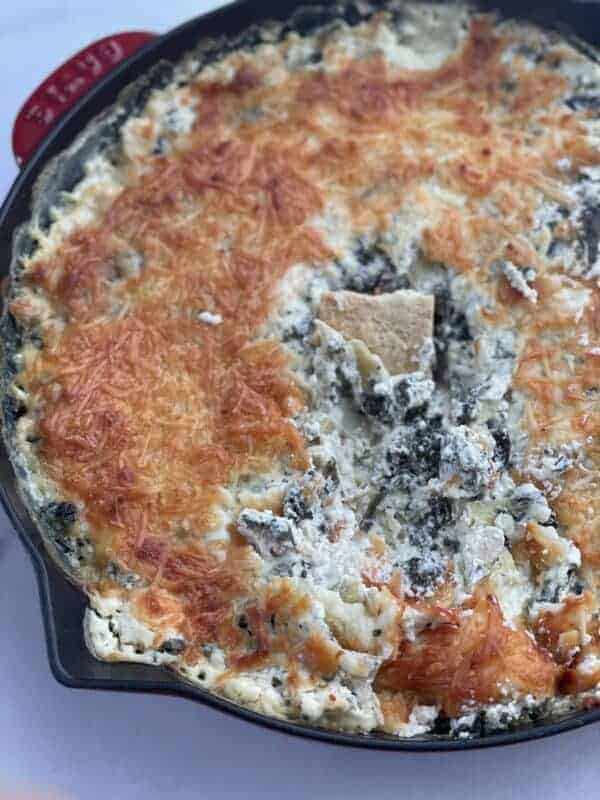 chicken spinach and artichoke dip being dipped into with a chip