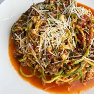 a bowl of low-carb baked spaghetti zoodles topped with grated Parmesan