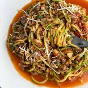 a bowl of low carb baked spaghetti zoodles with a bite being twirled around a fork