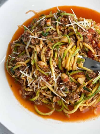a bowl of low carb baked spaghetti zoodles with a bite being twirled around a fork