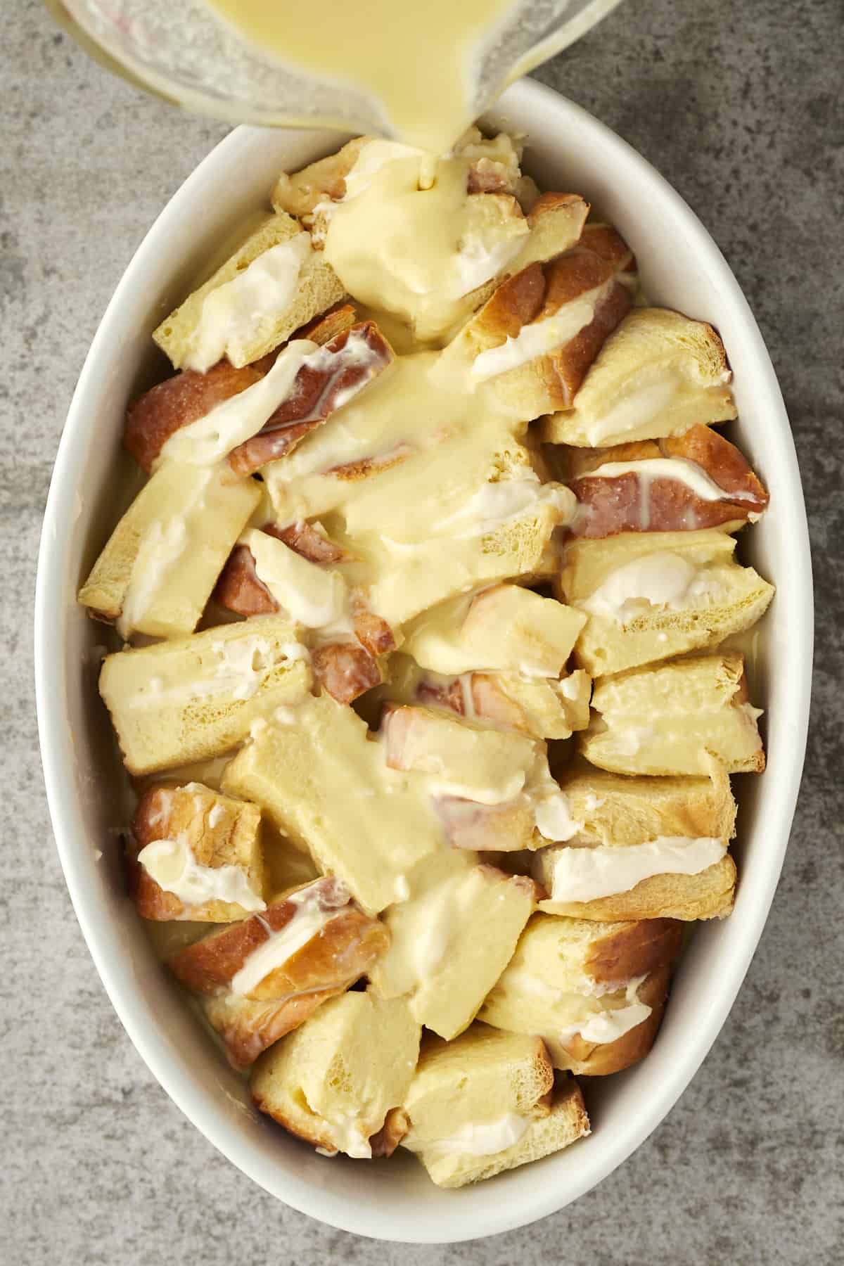 custard topping being poured over unbaked cannoli french toast