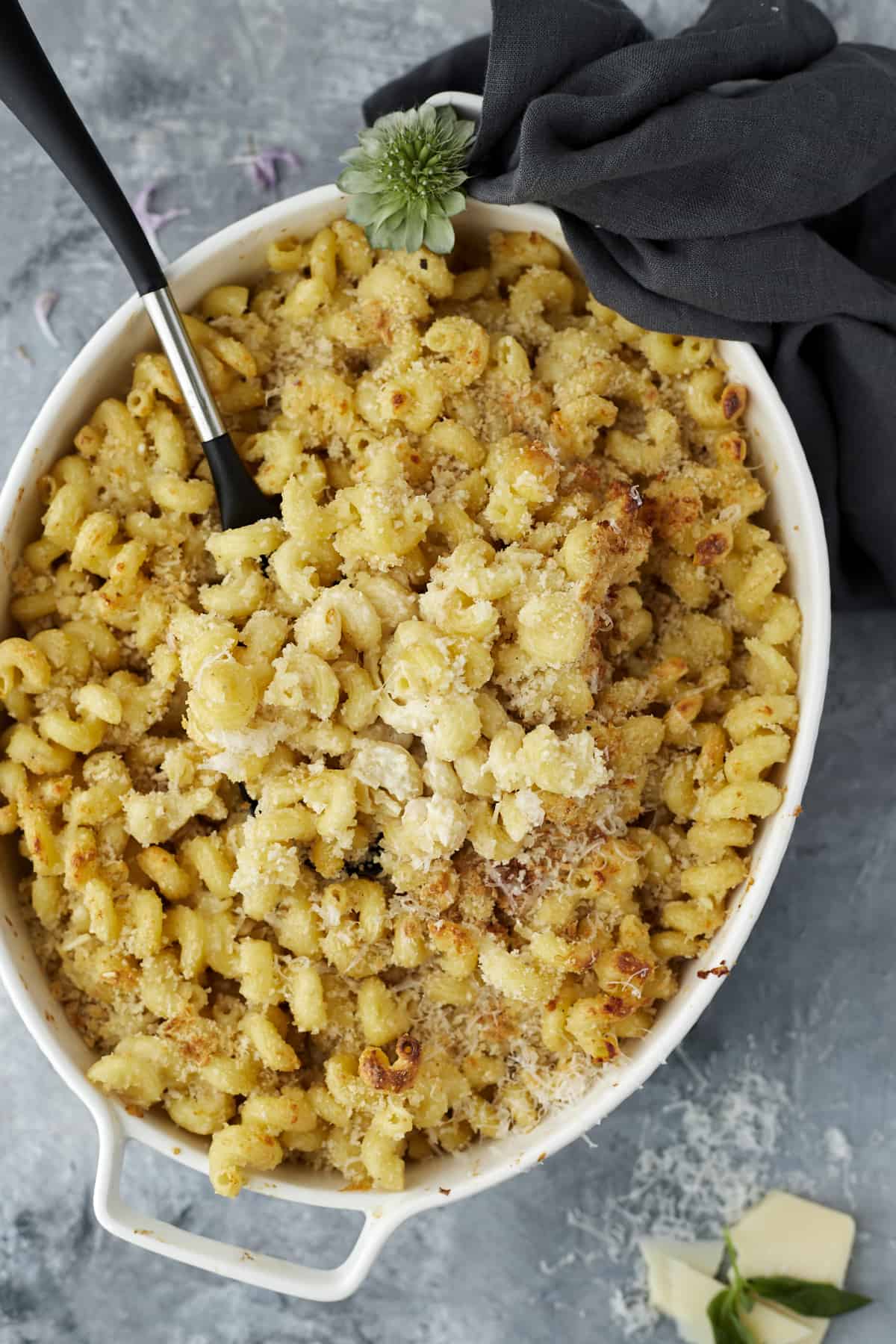 an oval baking dish full of easy baked mac and cheese with a spoon in the center.