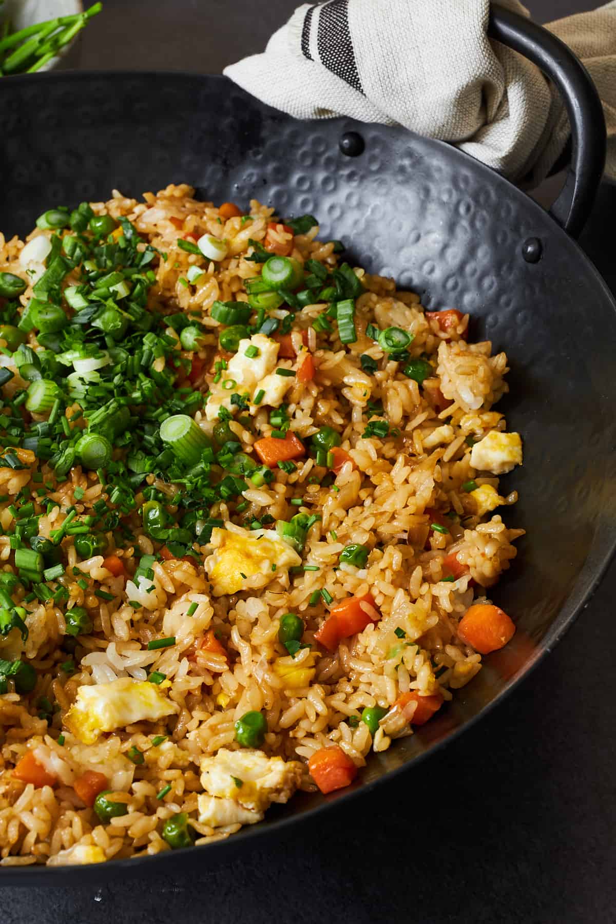 Egg fried rice in a wok topped with scallions. 