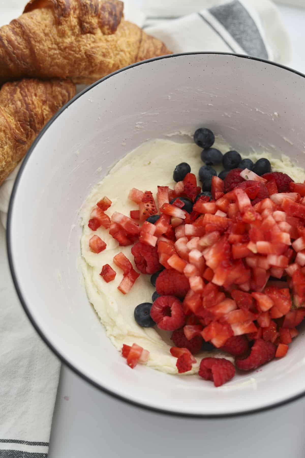 Blueberries, raspberries, and diced strawberries in a bowl with cream cheese