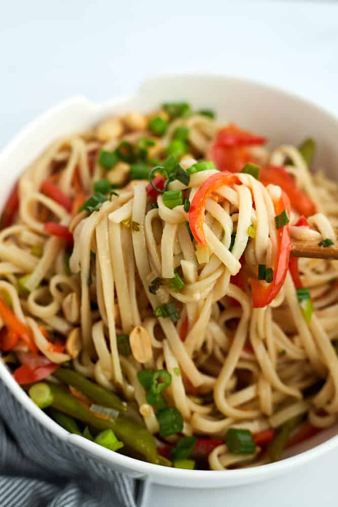 chopsticks scooping up a bite of vegetarian ramen from a bowl.