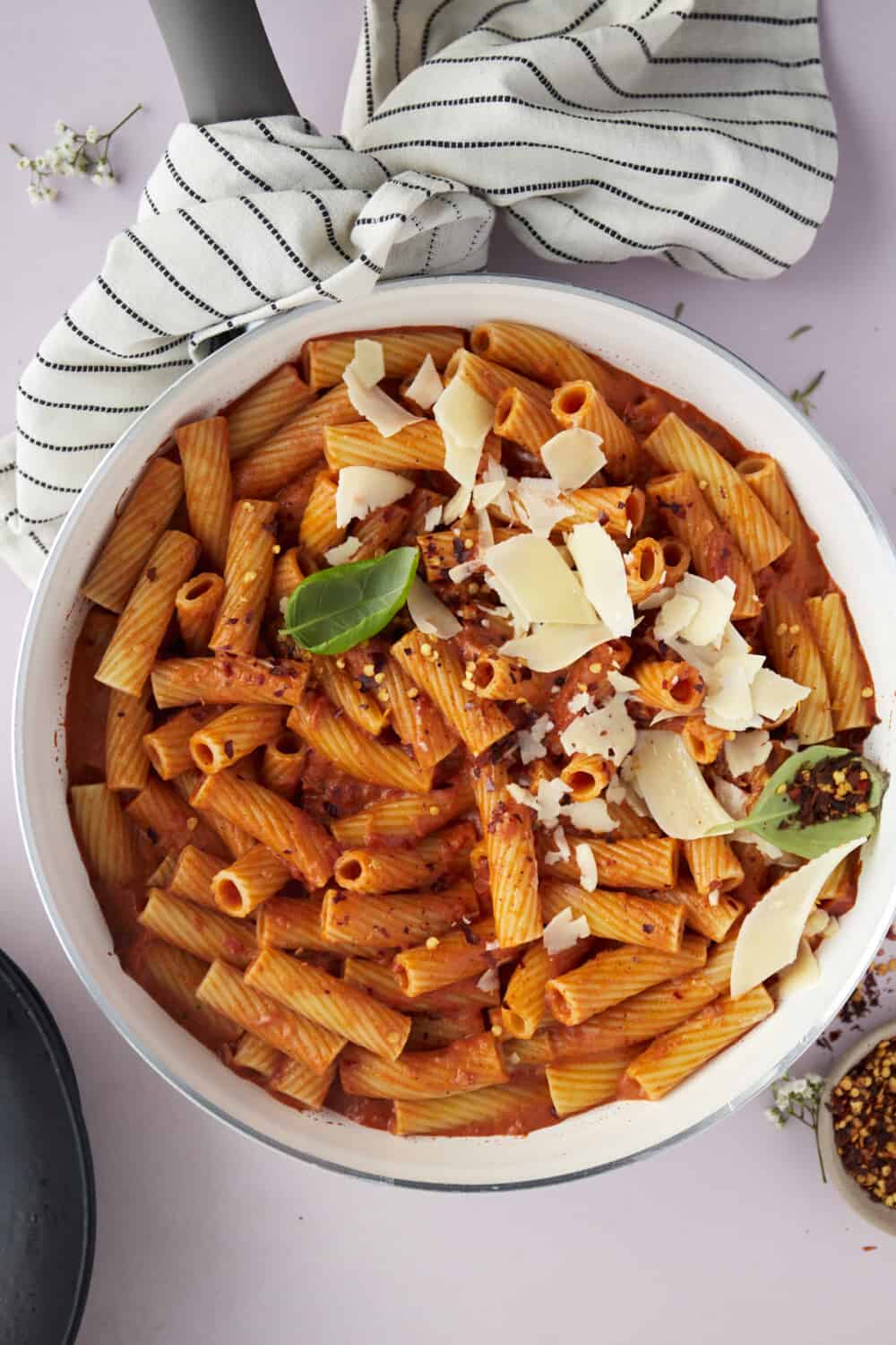 a large bowl full of spicy pasta topped with shaved Parmesan.