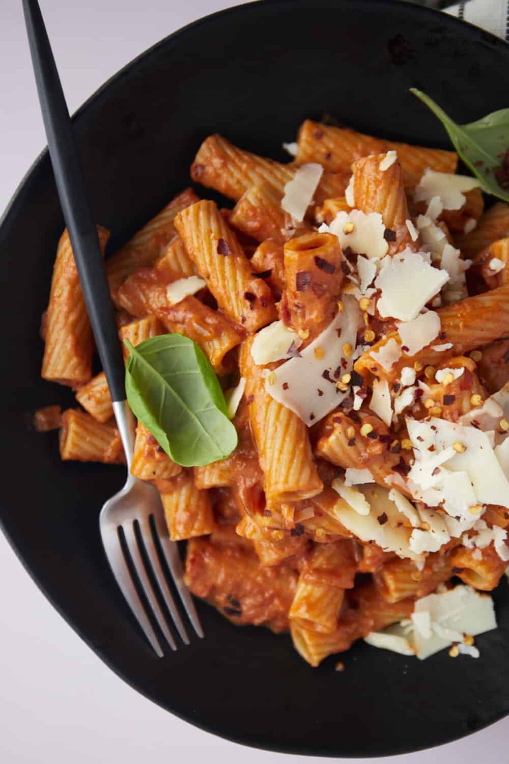close up image of a bowl of rigatoni pasta with a fork on the side.