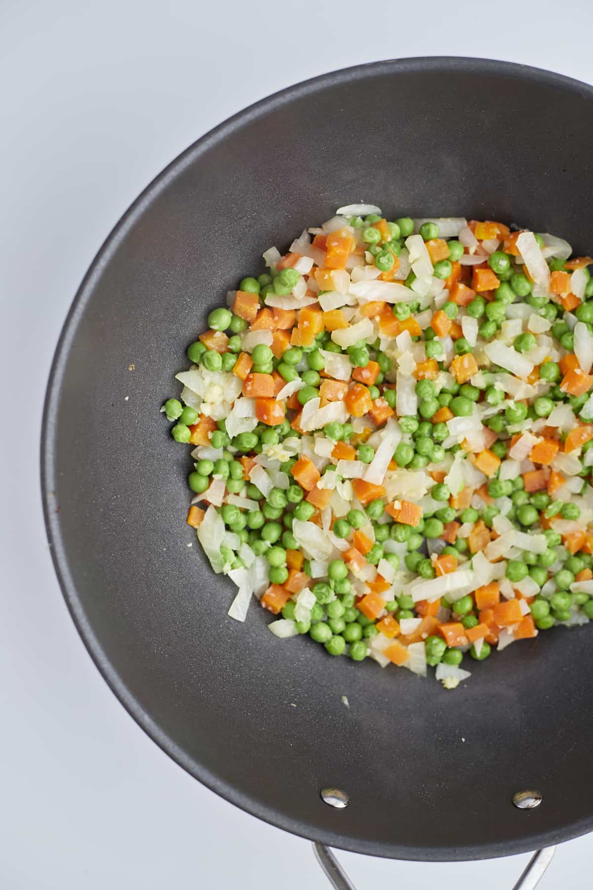 frozen peas and carrots with onions in a wok