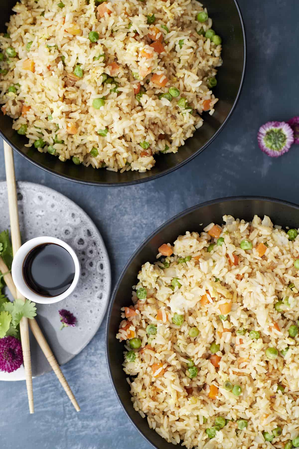 two plates full of wok egg fried rice with soy sauce on the side