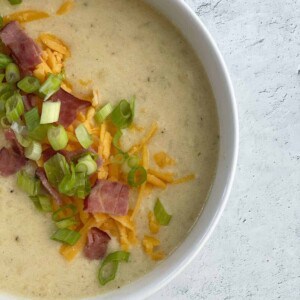 Crockpot potato soup topped with green onions, cheese, and bacon