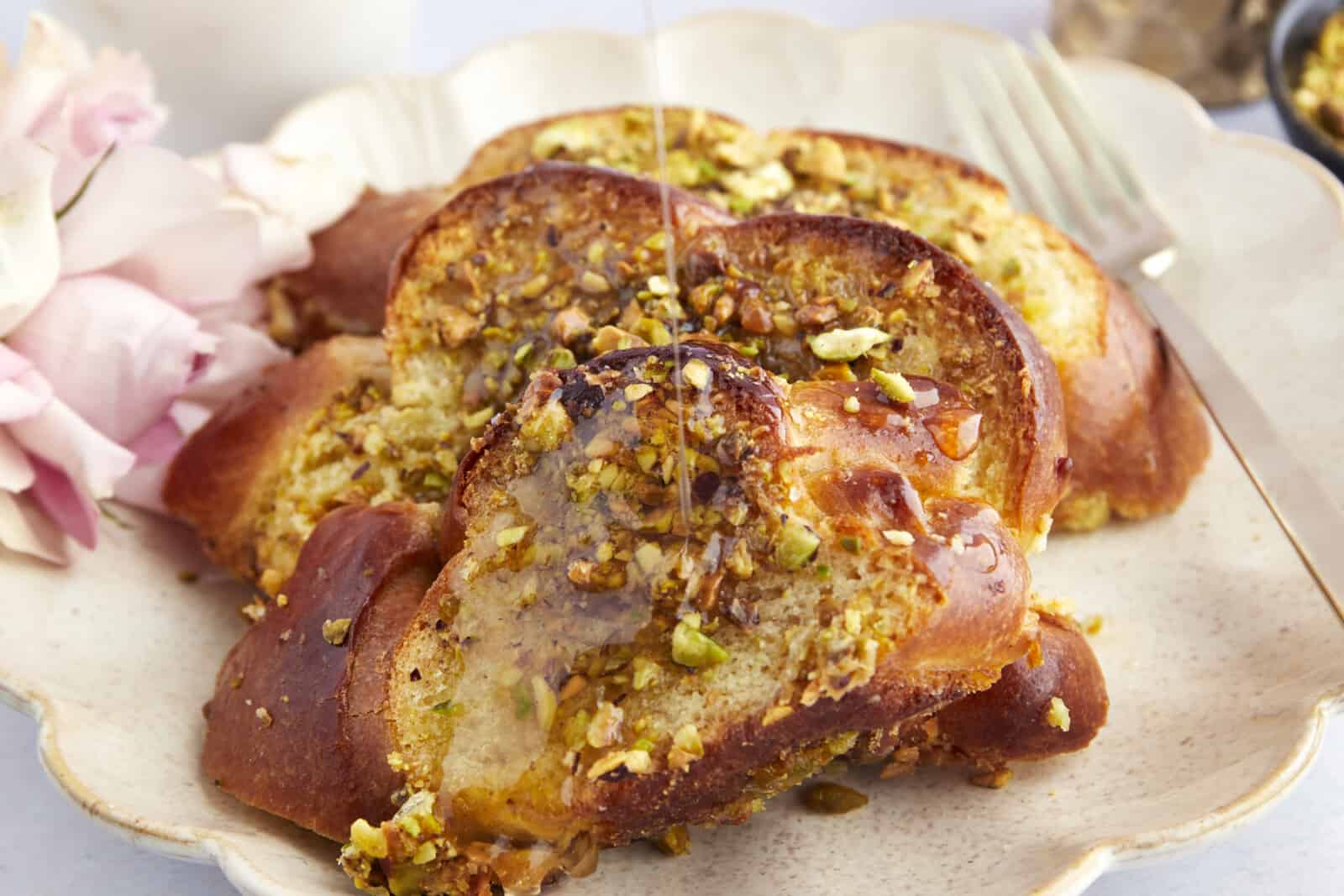 A plate of Baklava French toast with syrup being poured on top. 