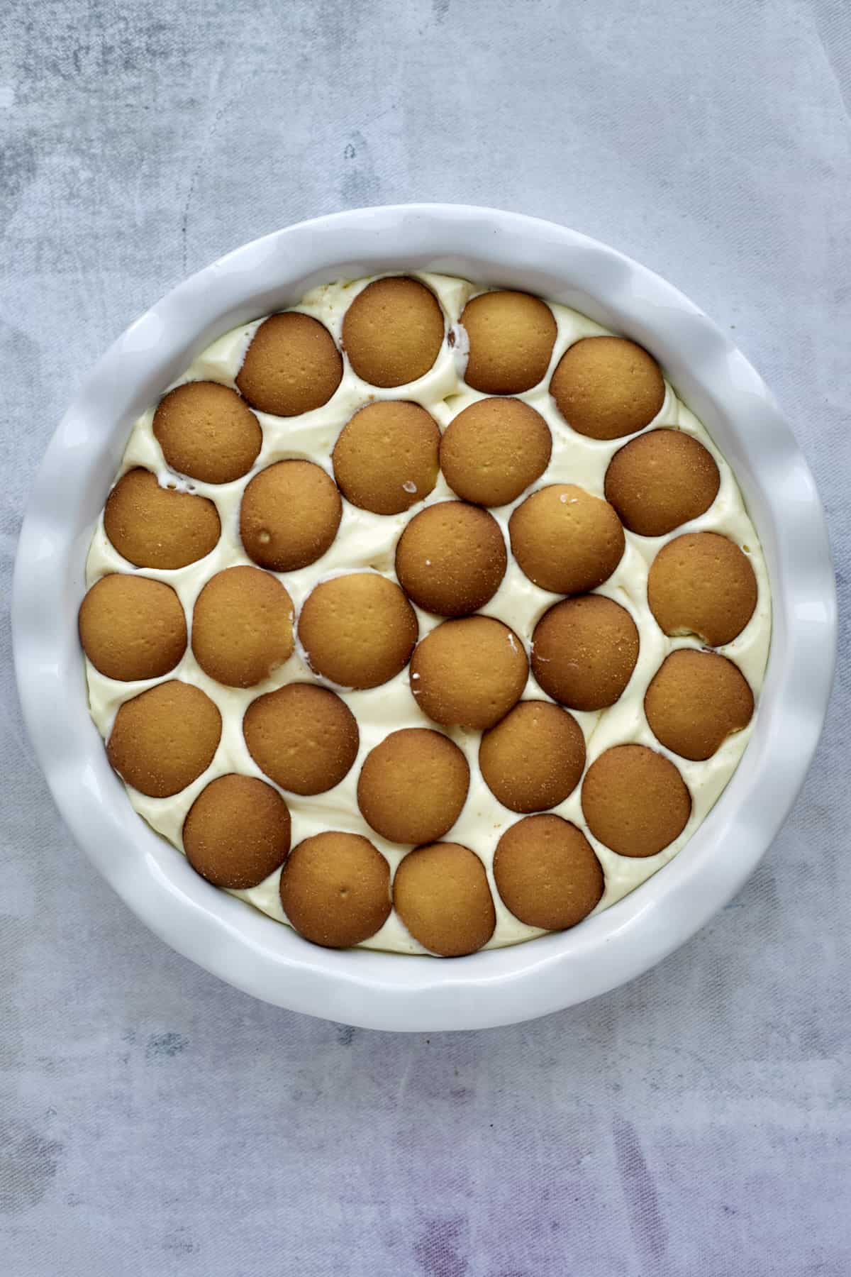 second layer of Nilla wafers over vanilla pudding filing in a baking dish.