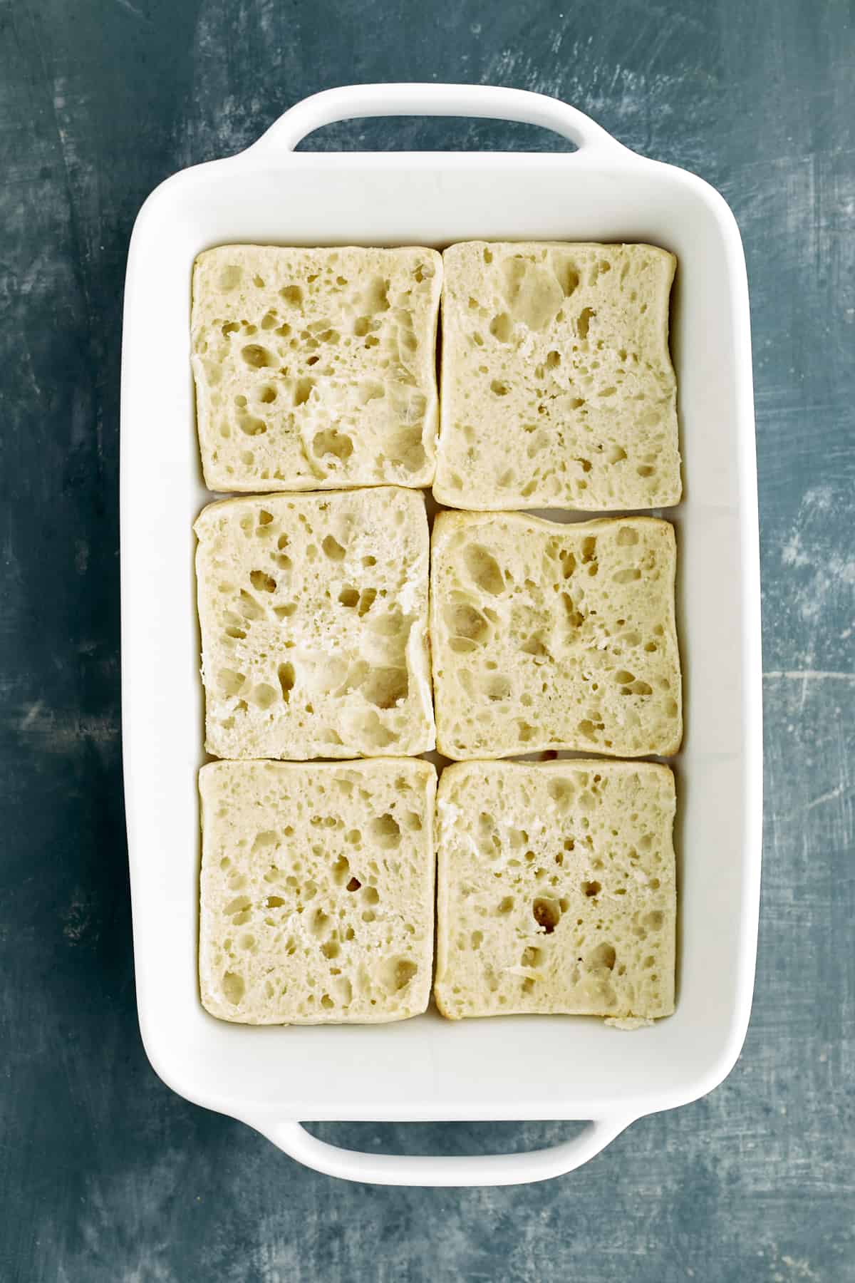 sliced ciabatta buns in a baking dish.