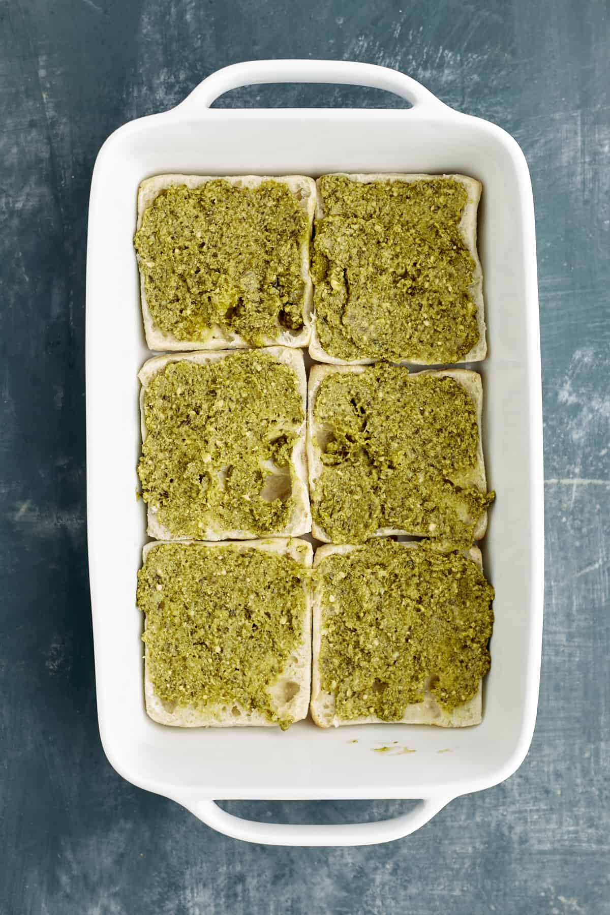 sliced bread in a baking dish topped with pesto.