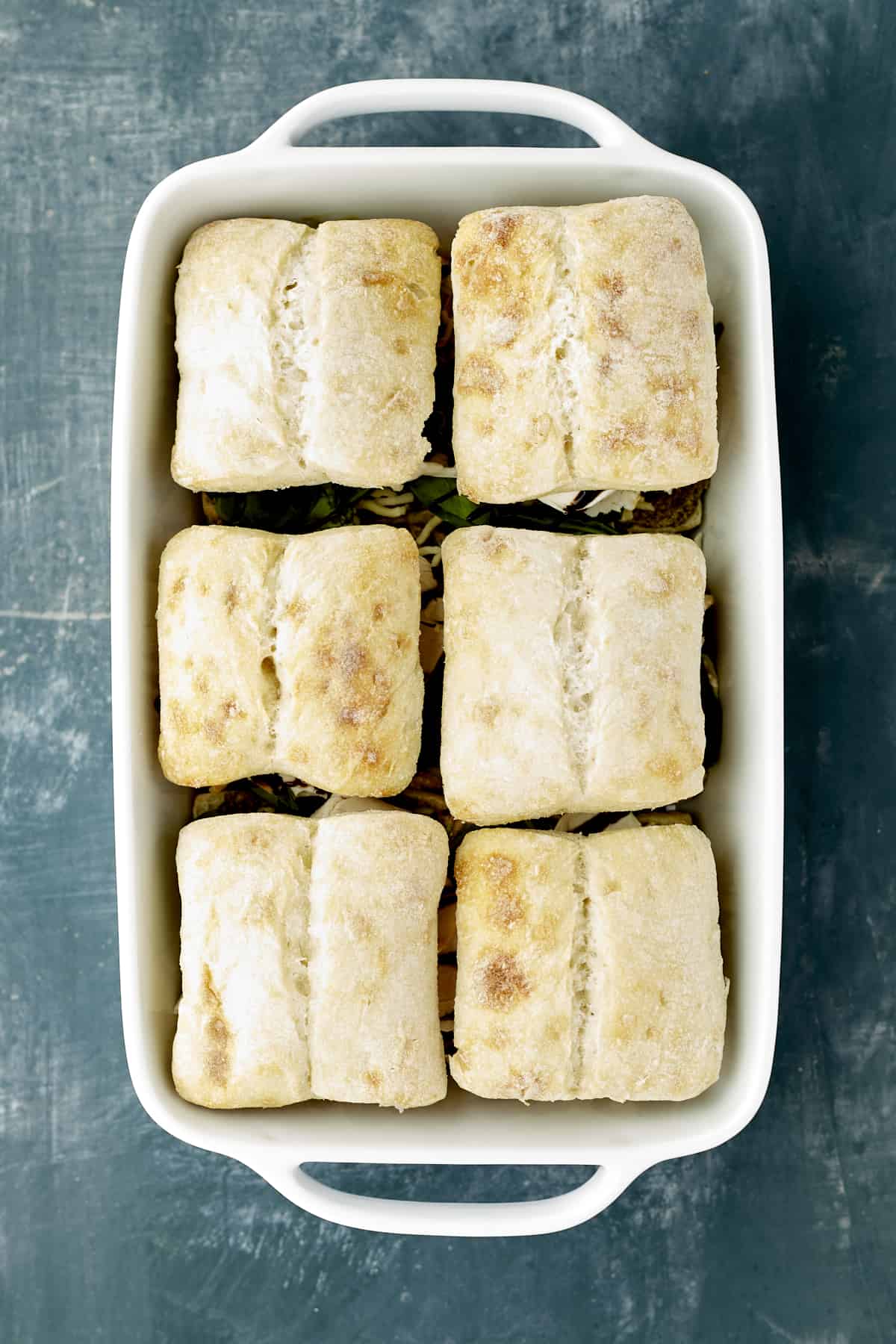 turkey caprese sandwiches in a white baking dish ready to be baked.