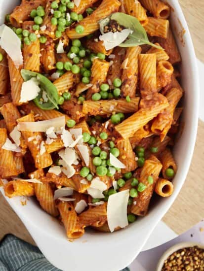 a casserole dish full of spicy baked rigatoni with peas and shaved Parmesan