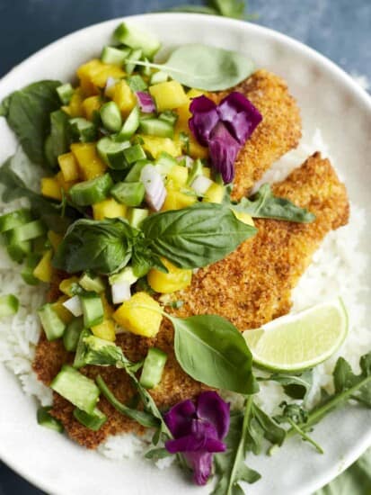 a plate full of tilapia and mango salsa over a bed of rice.