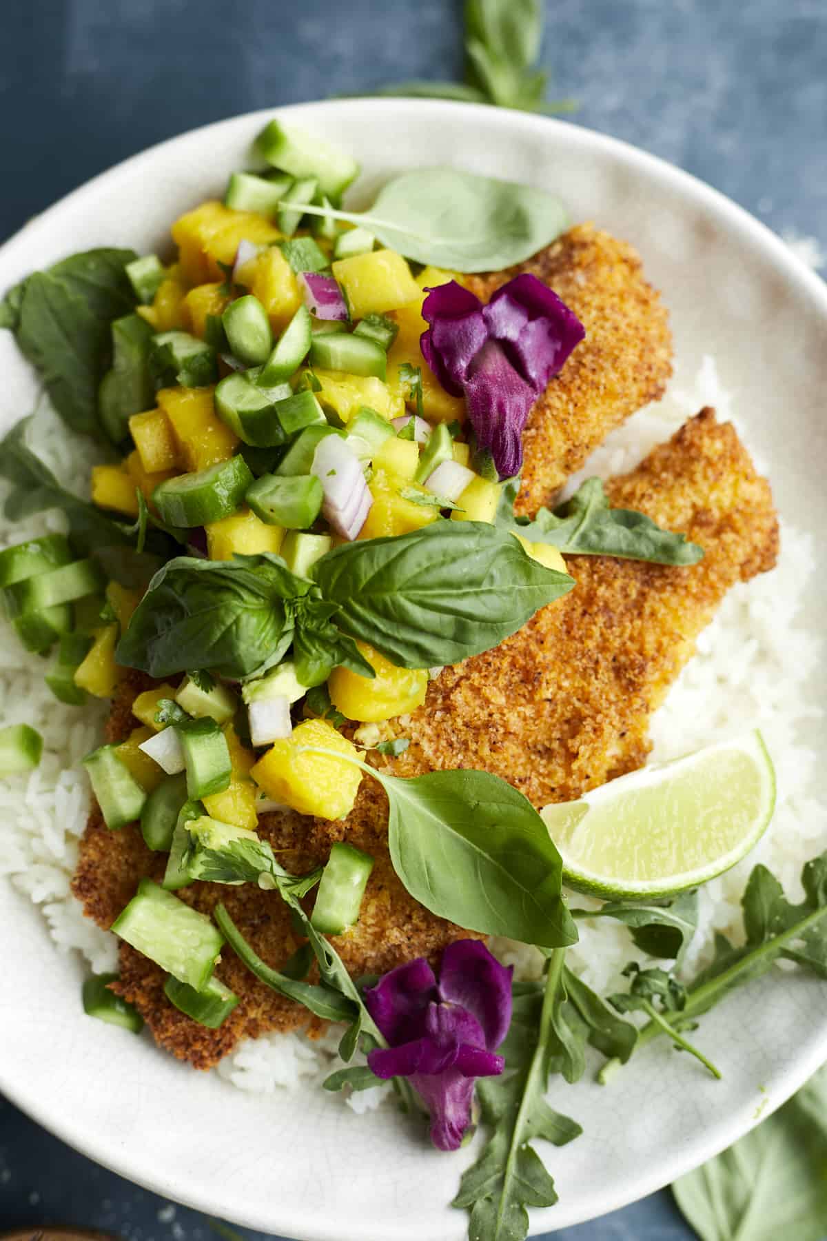 a plate full of tilapia and mango salsa over a bed of rice.
