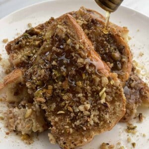 a plate of baklava french toast with honey being drizzled on top