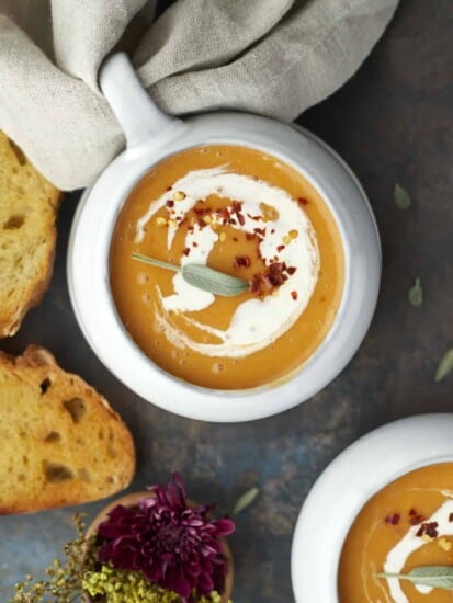 overhead image of a bowl of easy butternut squash soup with bread pieces around.