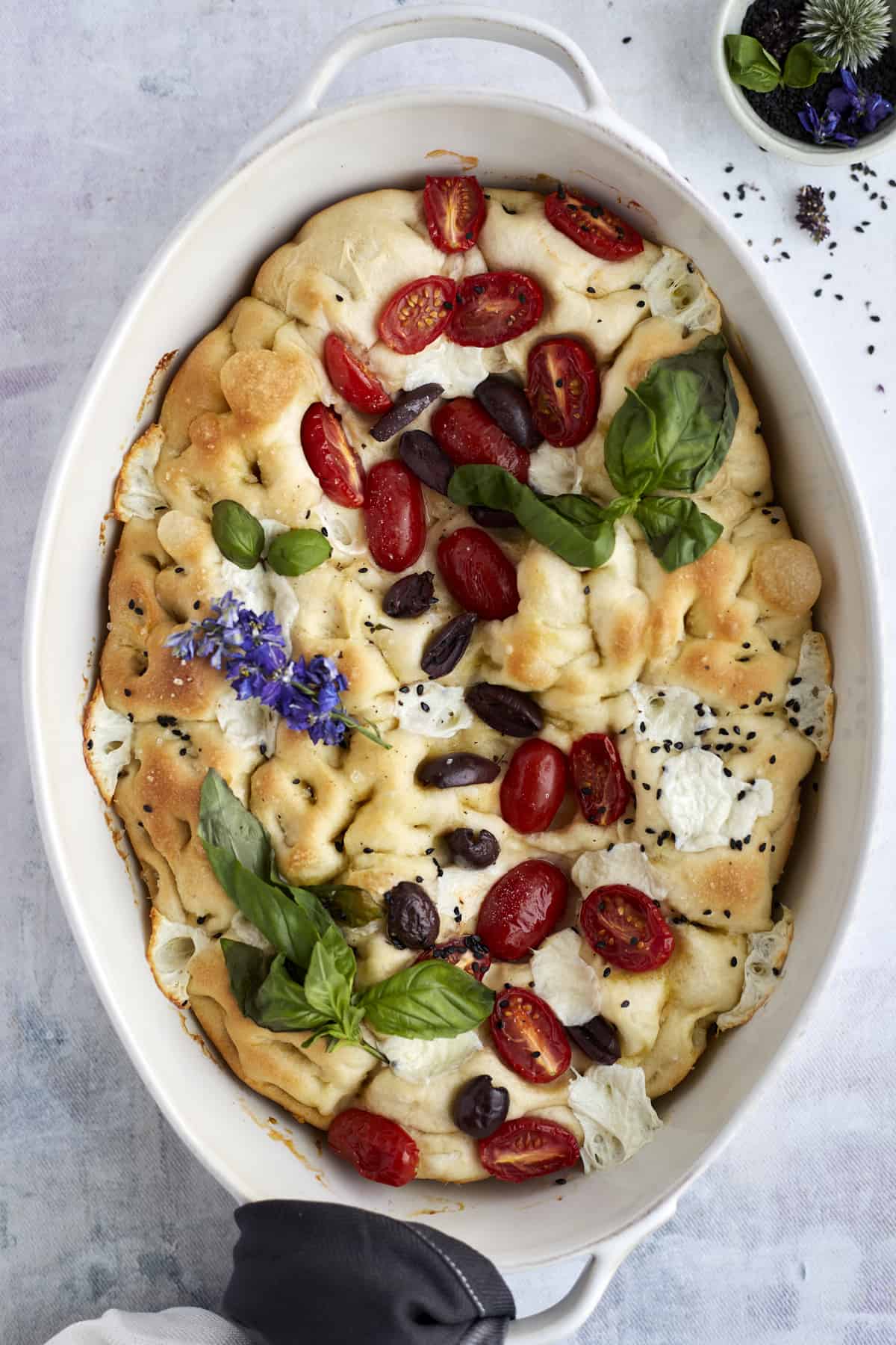 baked no knead focaccia bread with tomatoes, olives, fresh herbs, mozzarella, and herbs