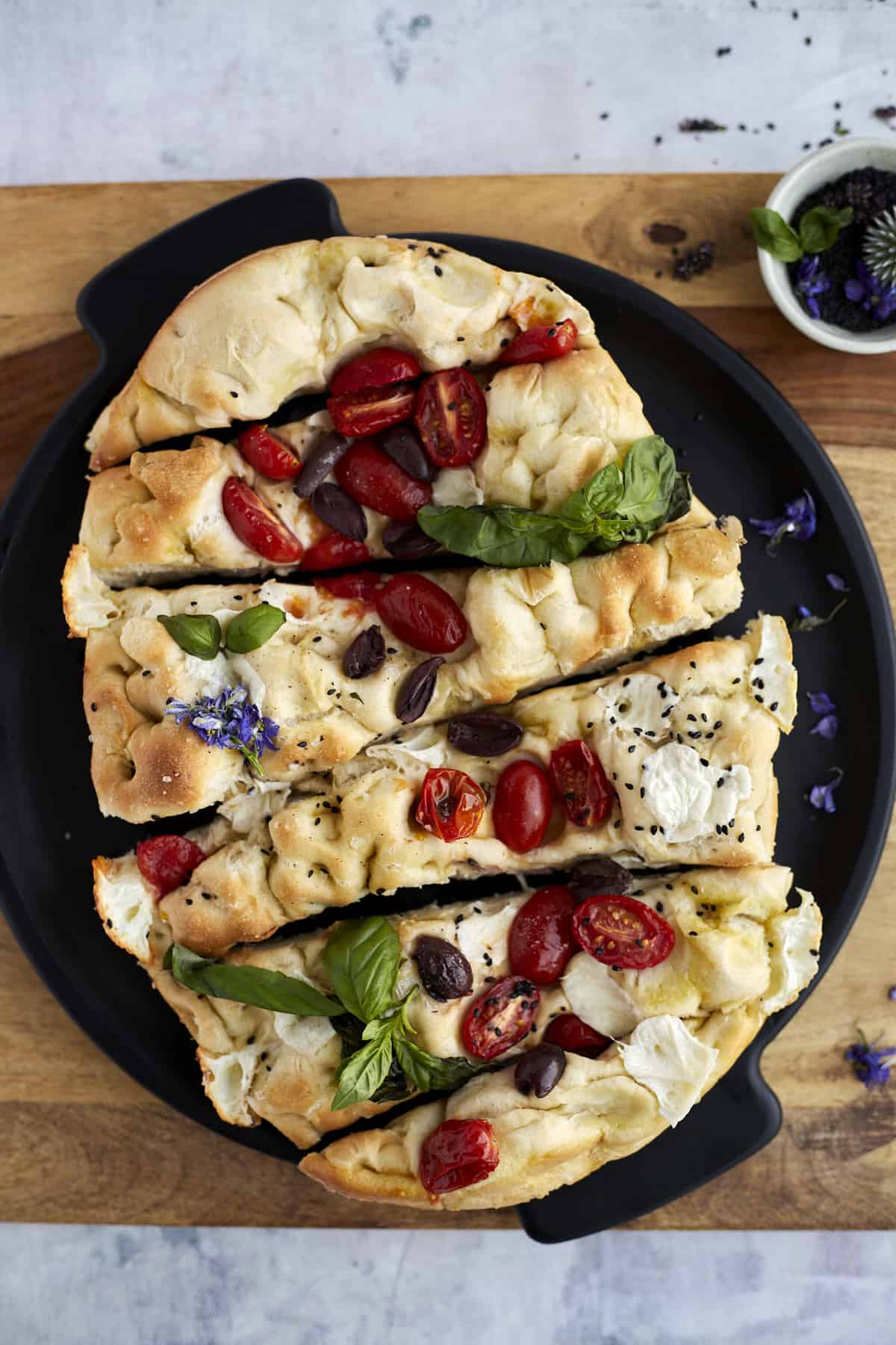 no knead focaccia bread topped with halved tomatoes and olives on a platter