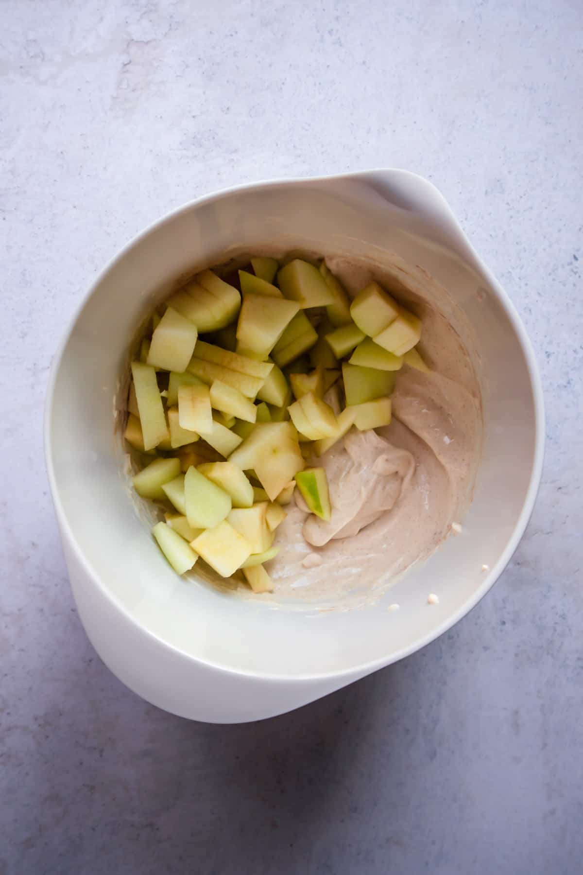 chopped apples on top of a cream cheese cinnamon mixture in a bowl 