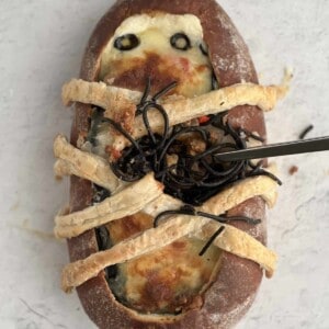 overhead image of a Halloween Squid Ink Spaghetti Bread Bowl with black quid ink spaghetti coming out of the middle