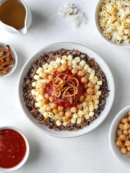 overhead large bowl of koshari with the fixings on top and the sides