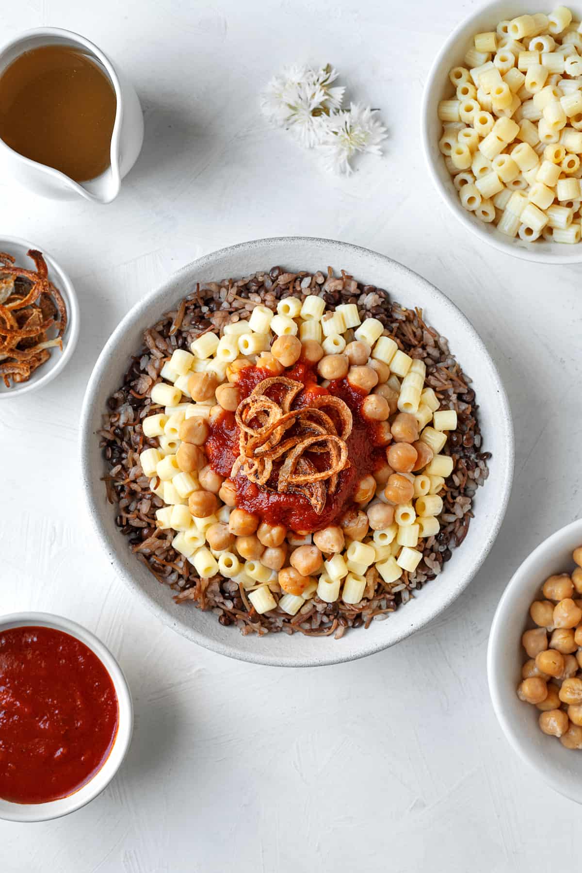 overhead large bowl of koshari with the fixings on top and the sides