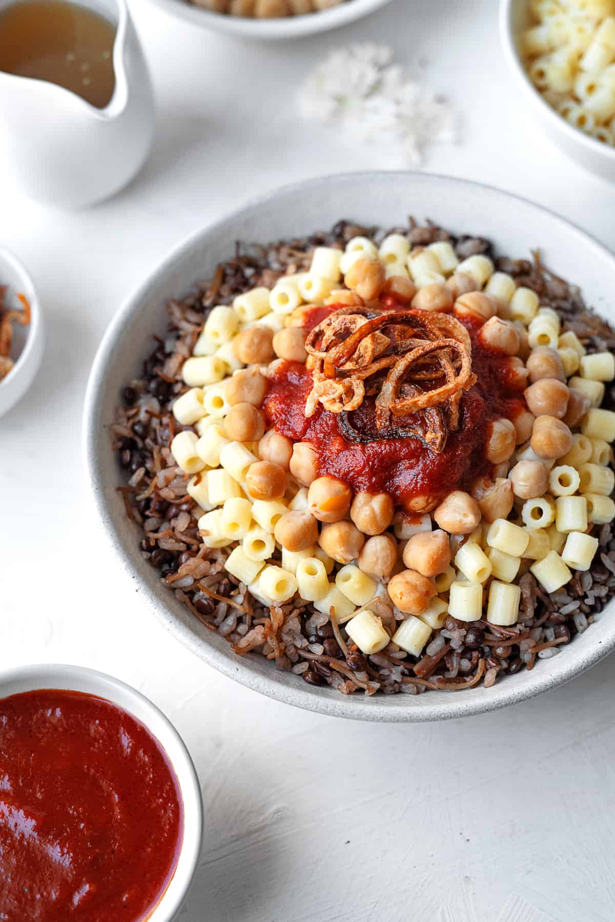 close up view bowl of koshari with the fixings on top and the sides