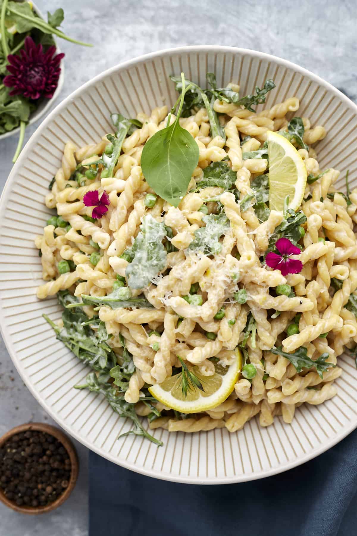 one pot lemon ricotta pasta in a white bowl with peas, herbs, and parmesan cheese