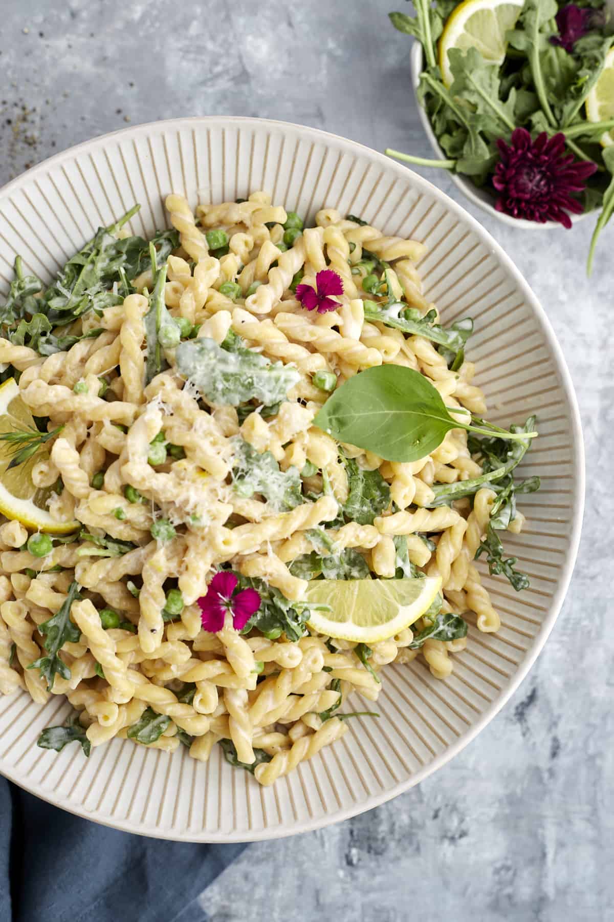 overhead image of a white bowl full of lemon ricotta pasta topped with fresh herbs and a lemon wedge