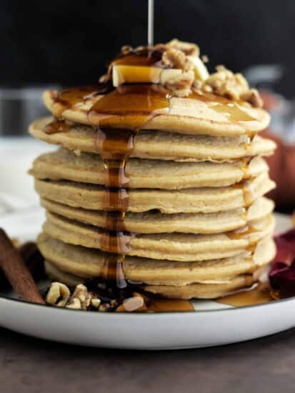 side view of a stack of high protein healthy pumpkin pancakes with maple syrup being drizzled on top