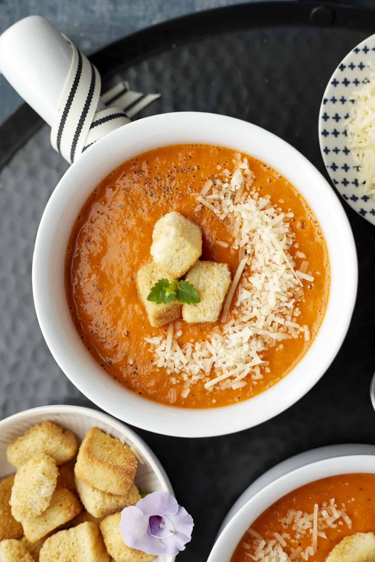 Overhead roasted tomato soup in a bowl with croutons and parmesan cheese.