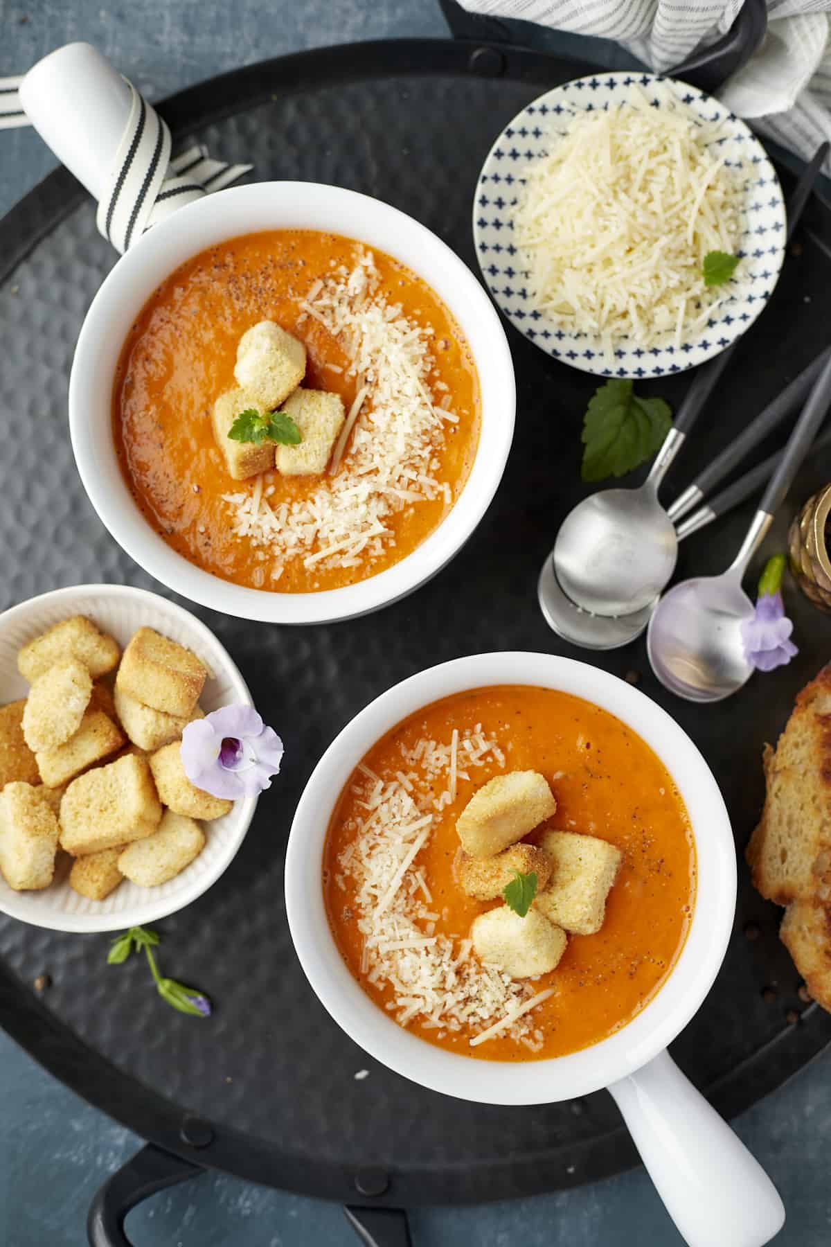 Roasted Tomato Soup with Parmesan Croutons. Two Soup Bowls garnish with parmesan cheese, croutons and basil.