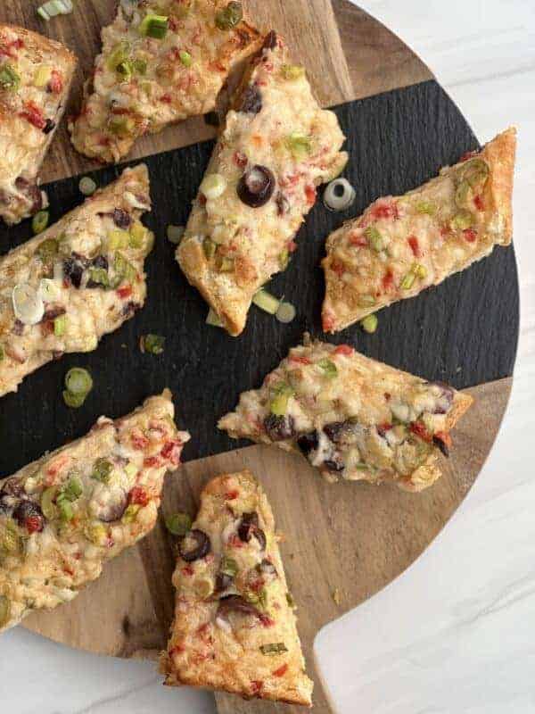 pieces of olive cheese bread on a cutting board