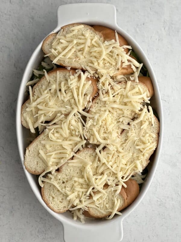 overhead image of Spinach and Artichoke Baked Grilled Cheese in a baking dish topped with cheese