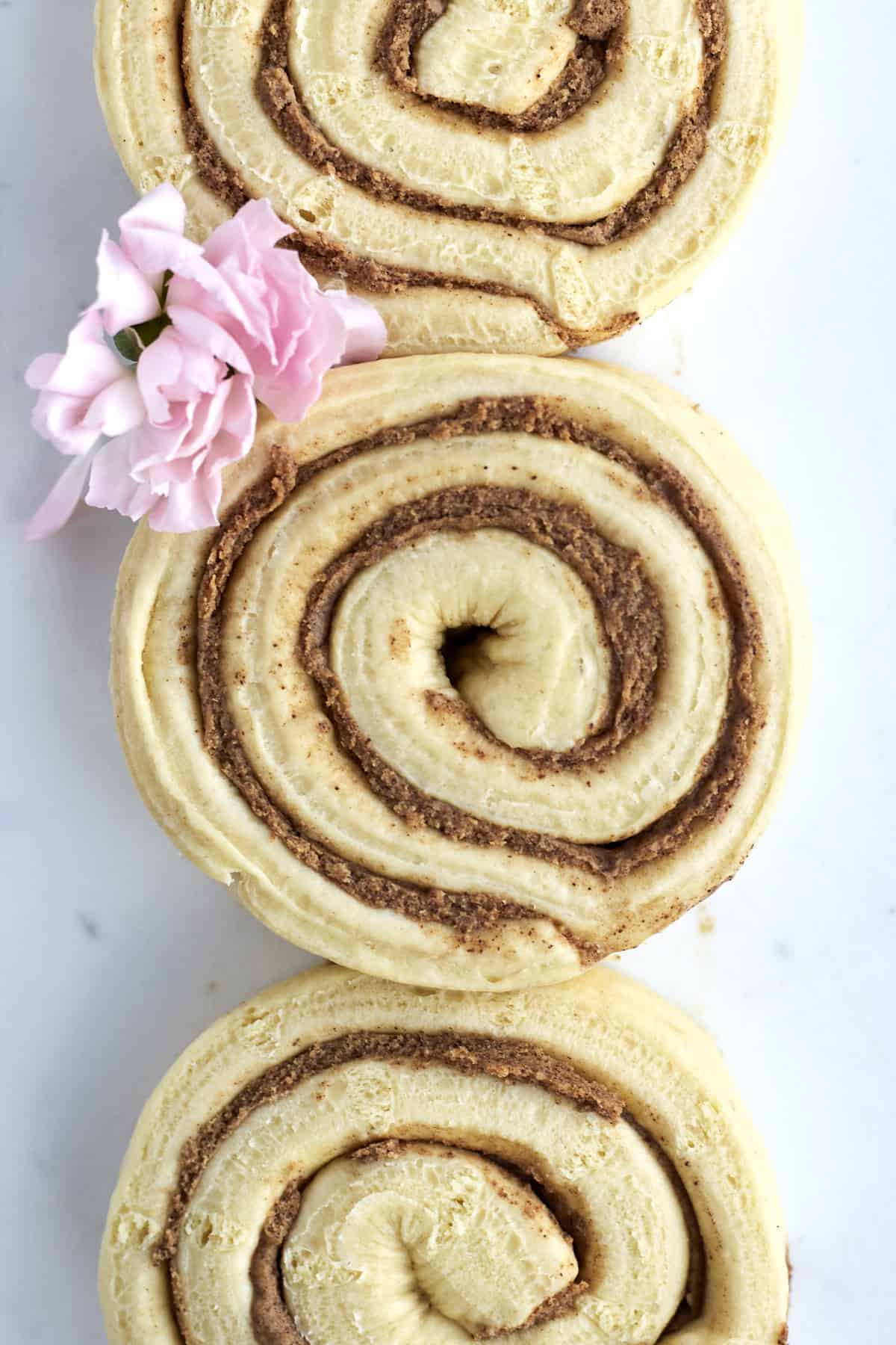 three rolls of unbaked cinnamon rolls in a vertical line.