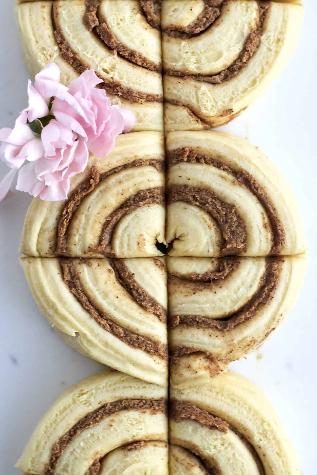 three unbaked cinnamon rolls that have been sliced into quarters.
