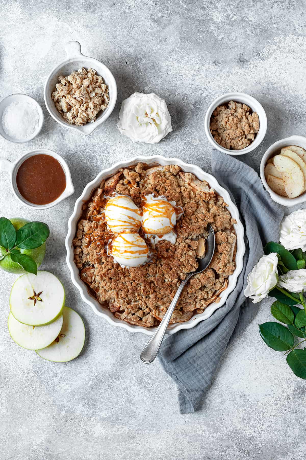 overhead image of an apple crisp topped with three vanilla ice cream scoops and a drizzle of caramel