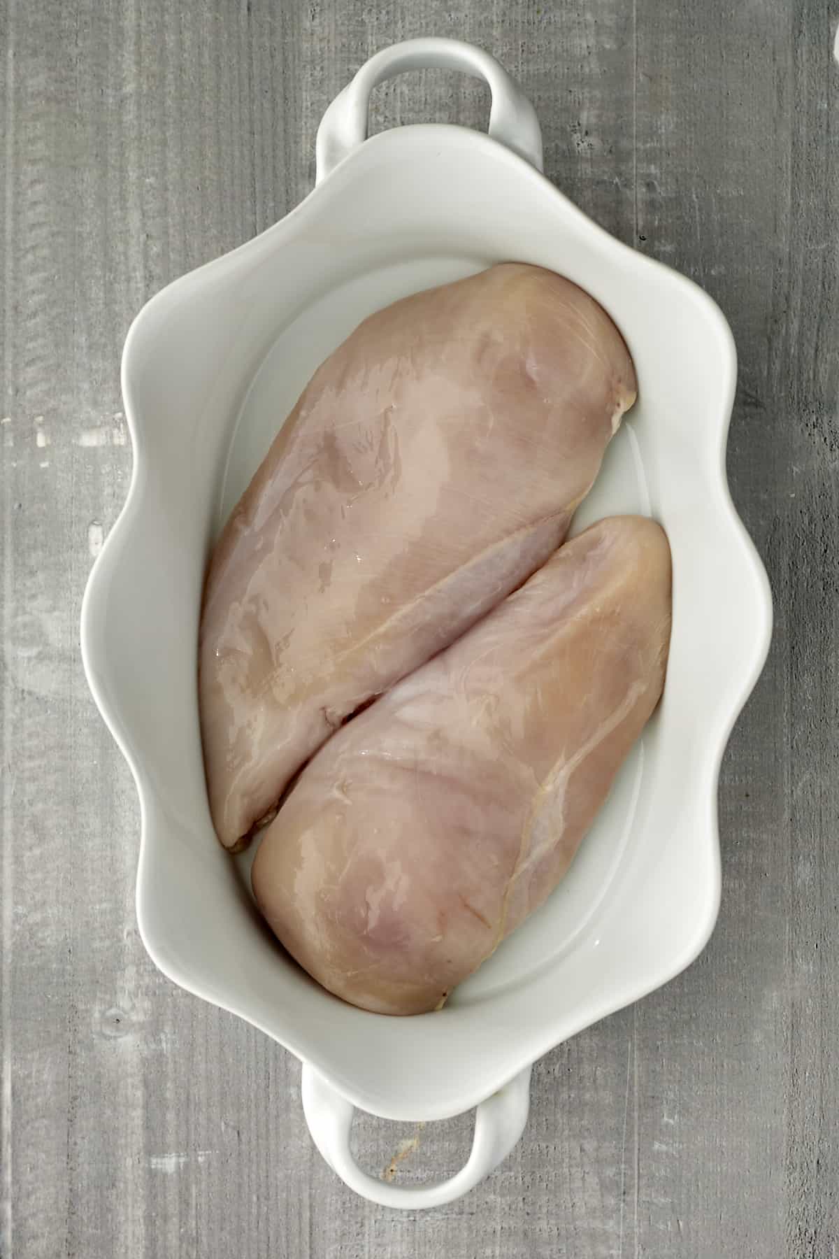 raw chicken breasts in a white baking dish