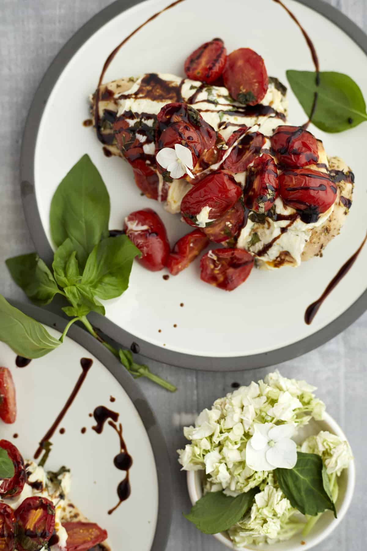 a plate with baked bruschetta chicken topped with mozzarella, tomatoes, balsamic vinegar, and basil