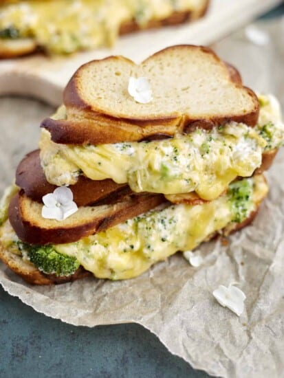 two roasted garlic and broccoli oven grilled cheese sandwiches on parchment paper.