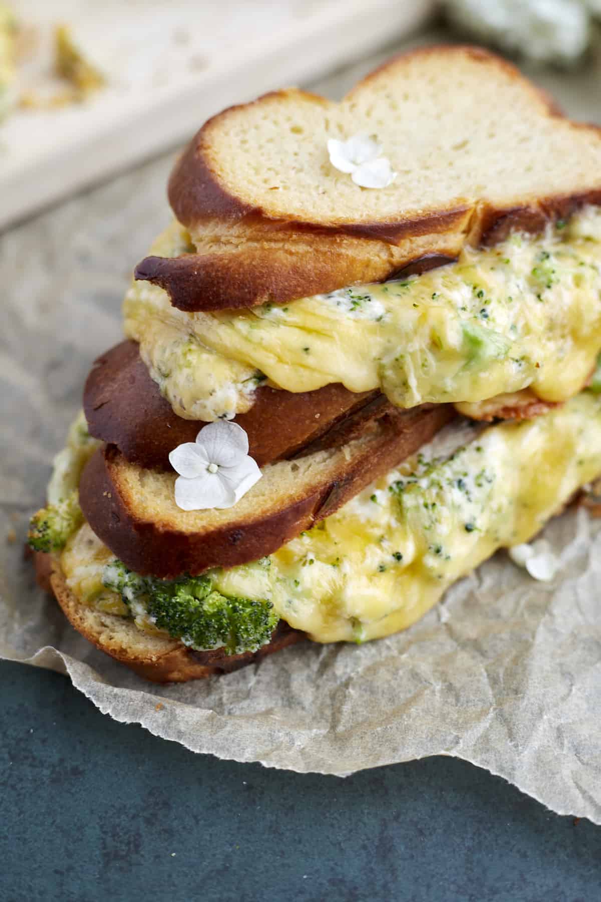 close up image of two roasted garlic and broccoli oven baked grilled cheese sandwiches stacked on top of each other 