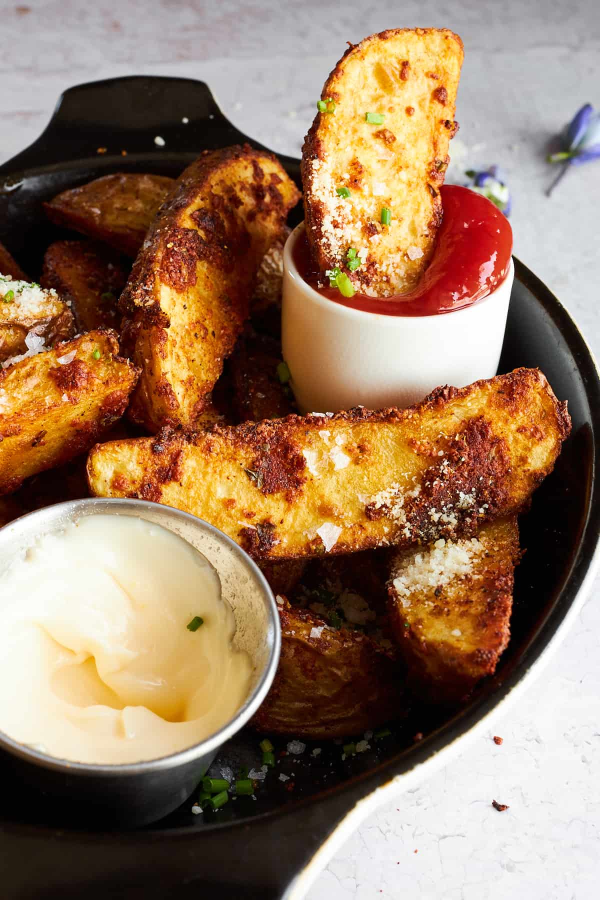 Garlic parmesan potato wedges on a plate with dipping sauces. 